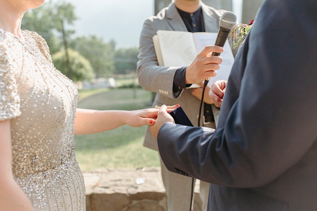 groom placing ring on brides finger at cathedral park wedding ceremony