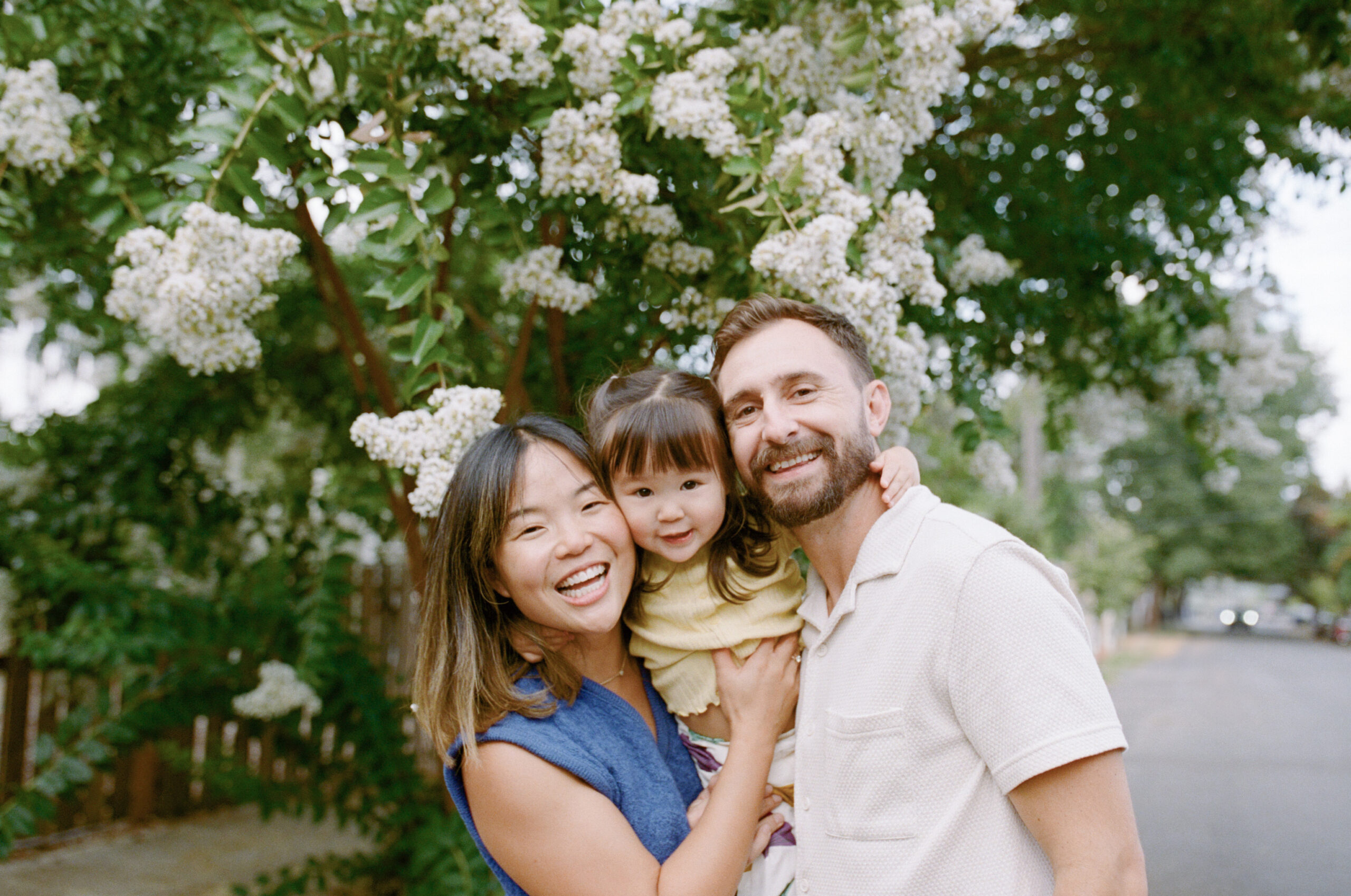 Family smiling in front of blossoming tree in north portland, oregon.